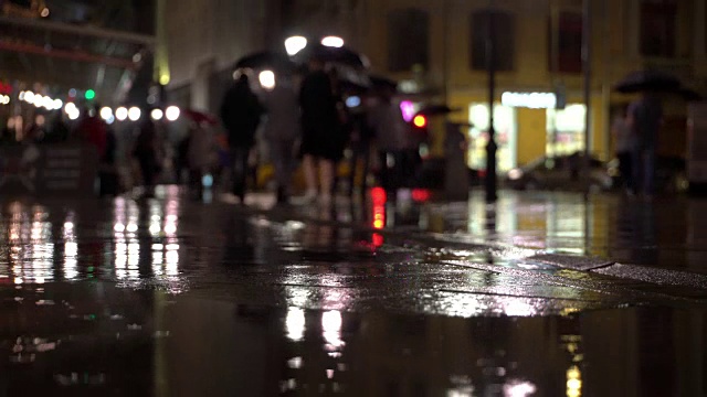 详情图-雨夜，在路灯的照耀下，雨点落在五颜六色的沥青上。不认识的人在雨伞下走，过有红绿灯的马路。美丽的彩色的散景。天气、交通、城市街道、现代城市生活方式的概念