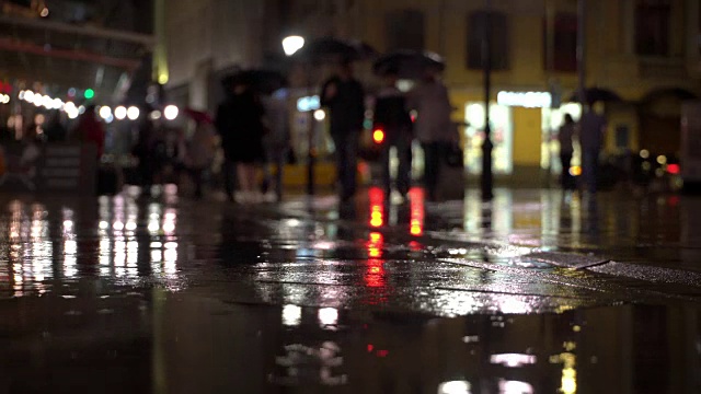 详情图-雨夜，在路灯的照耀下，雨点落在五颜六色的沥青上。不认识的人在雨伞下走，过有红绿灯的马路。美丽的彩色的散景。天气、交通、城市街道、现代城市生活方式的概念