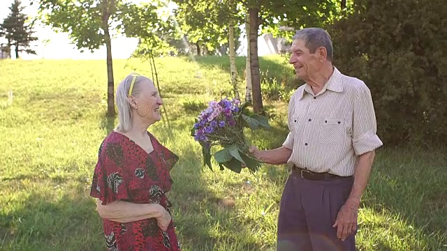 在公园里，老人给心爱的妻子送花。