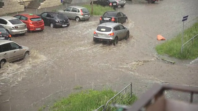 汽车在雨中行驶在被洪水淹没的道路上，慢镜头