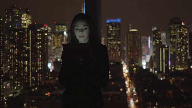 迷人的黑发女人在办公室工作。商业女性工作与数字平板电脑在办公室与城市景观。