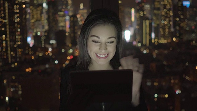 迷人的黑发女人在办公室工作。商业女性工作与数字平板电脑在办公室与城市景观。