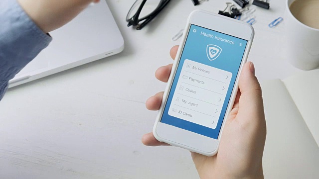 坐在办公桌前使用智能手机应用程序支付医疗保险