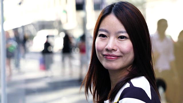 美丽的亚洲女人穿着漂亮的衣服站在城市的环境。城市生活背景。