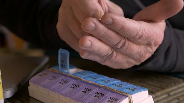 一个男人的手的特写装满了他的每日药丸计划与药物
