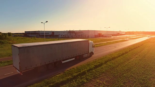 詳情圖-在高速公路上移動的白色半掛車的鳥瞰圖。在背景中可以看到倉庫和工業(yè)裝載建筑。日落。