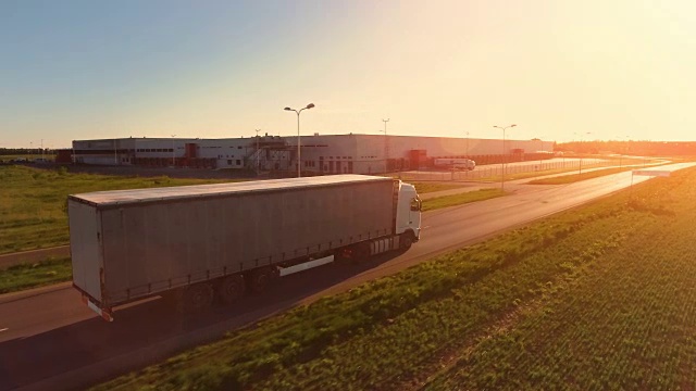 詳情圖-在高速公路上移動的白色半掛車的鳥瞰圖。在背景中可以看到倉庫和工業(yè)裝載建筑。日落。
