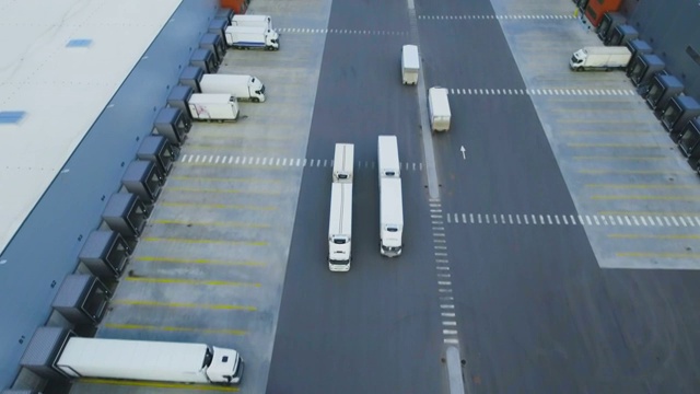 詳情圖-空中拍攝的卡車與掛載半掛車離開工業(yè)倉庫/倉庫大樓/裝卸區(qū)的許多卡車裝載/卸載商品。