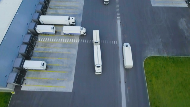 詳情圖-空中拍攝的卡車與掛載半掛車離開工業(yè)倉庫/倉庫大樓/裝卸區(qū)的許多卡車裝載/卸載商品。