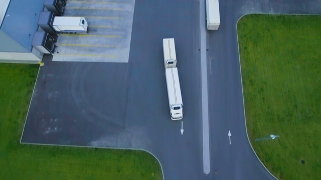 詳情圖-空中拍攝的卡車與掛載半掛車離開工業(yè)倉庫/倉庫大樓/裝卸區(qū)的許多卡車裝載/卸載商品。