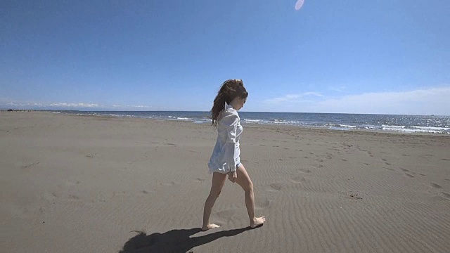 美丽的年轻女子吹头发手臂举起，黑发女子在海滩上跑步享受生活，慢动作