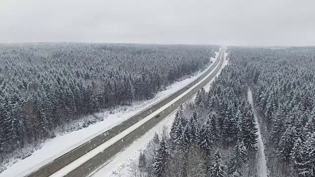 4 k。在冬天的森林里开着车在下雪。空中全景。消失点的角度来看