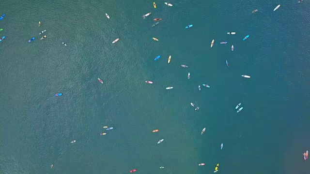 空中顶下冲浪者在多彩的冲浪板上排队等待赶上一个浪