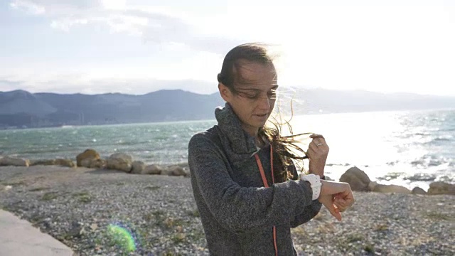 年轻女子跑步，在运动手表上查看她的有氧训练数据。