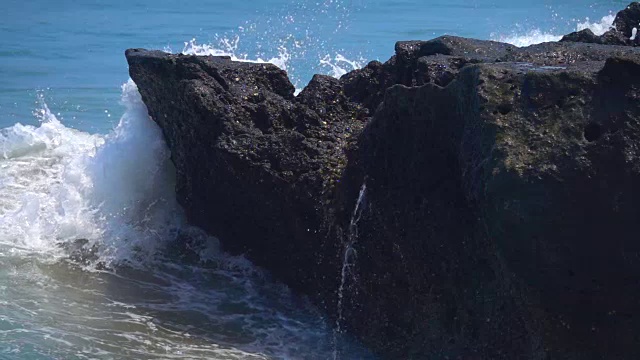 慢动作:海浪撞击黑色的火山岩，溅起水珠