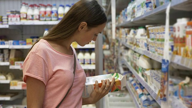 在购物中心的食品杂货店里，一位女士在冰箱里挑选乳制品