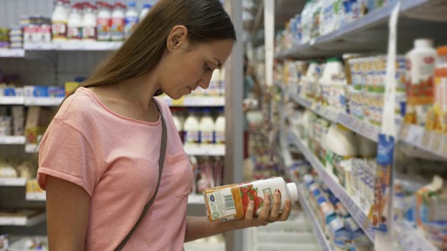 在购物中心的食品杂货店里，一位女士在冰箱里挑选乳制品