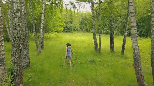 俯瞰森林里的年轻女子。在白桦林微笑的女孩