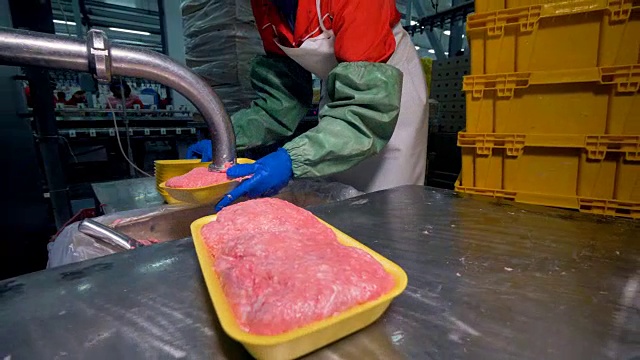 一名工人用许多塑料托盘来包装碎肉。