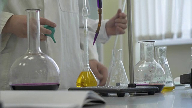 实验室技术员在实验室做实验。男性医学或科学实验室研究人员用蓝色液体进行测试。在实验室里用烧瓶工作的科学家