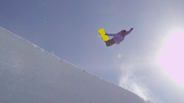 详情图-慢动作:年轻的职业滑雪板运动员在阳光灿烂的雪公园半管跳跃
