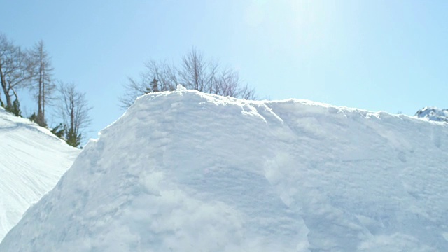 慢动作:滑雪板跳过踢球，在阳光灿烂的雪园飞过太阳