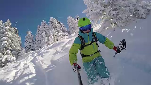 慢动作:极限自由式滑雪者在阳光明媚的山上骑着新鲜的粉末雪