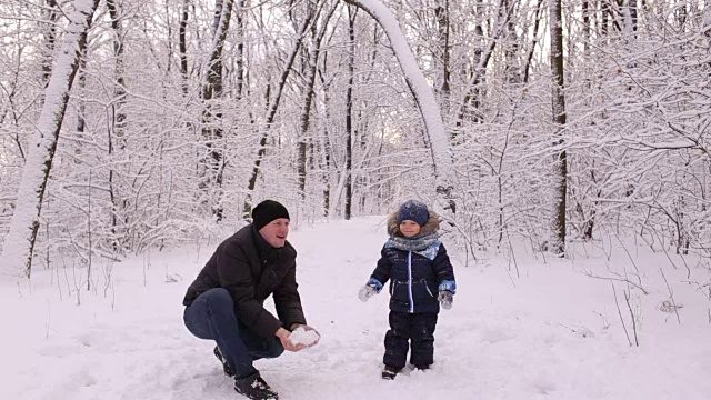 年轻的爸爸和他的小儿子在玩雪