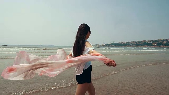 戴着围巾在海边散步的女人