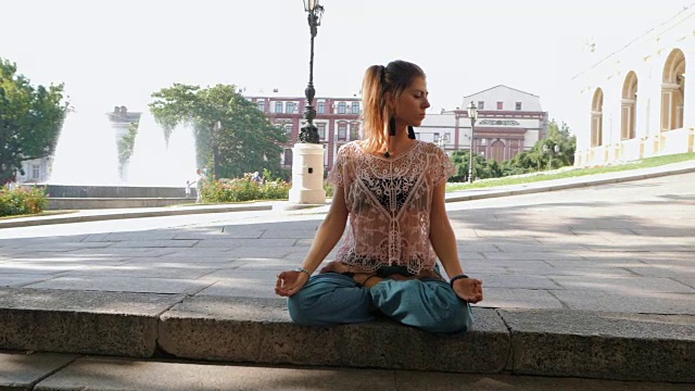 详情图-一个女人在楼梯顶上莲花姿势冥想。年轻女孩在繁忙的城市背景下做瑜伽。慢动作