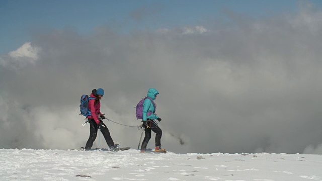 两名女登山家正在穿越冰川，云层正在逼近。