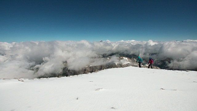 两名女性登山者用绳子系在一起攀登冰川。