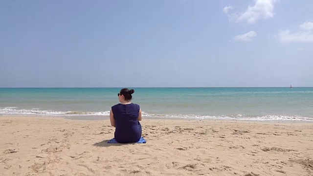 一个女人坐在沙滩上的慢镜头