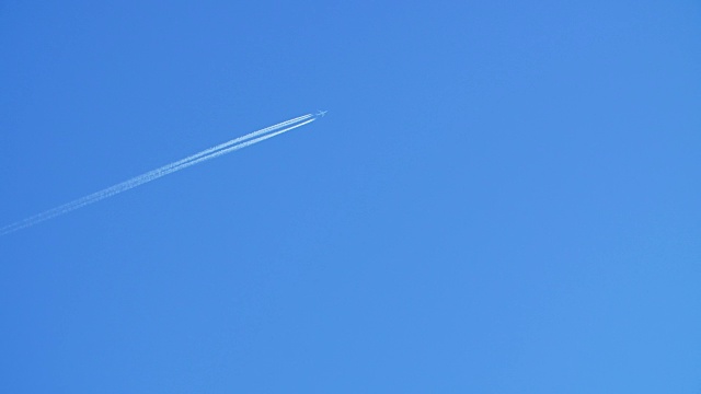 一架喷气式客机在高空飞行，在清澈的蓝天上留下了尾迹。
