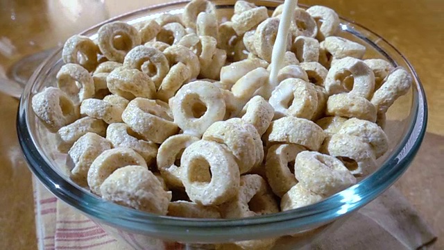 脆燕麦片在碗里，早餐美味的牛奶。慢动作旋转跟踪镜头。