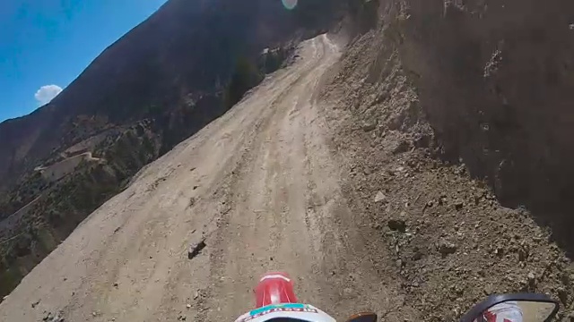 一个骑摩托车的人在一条危险的山路上行驶
