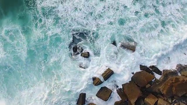 海浪在岩石海滩傍晚鸟瞰图