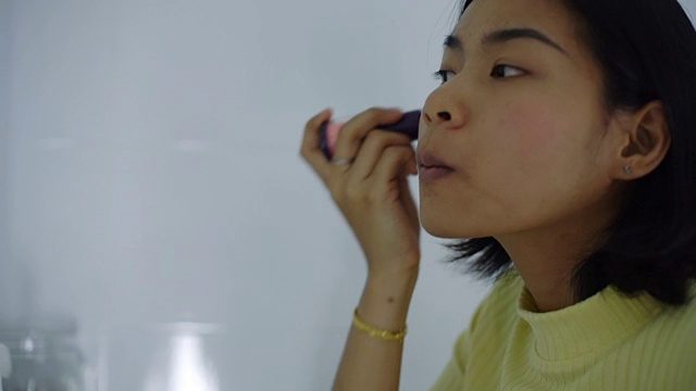 亚洲妇女，在脸颊上涂抹胭脂粉