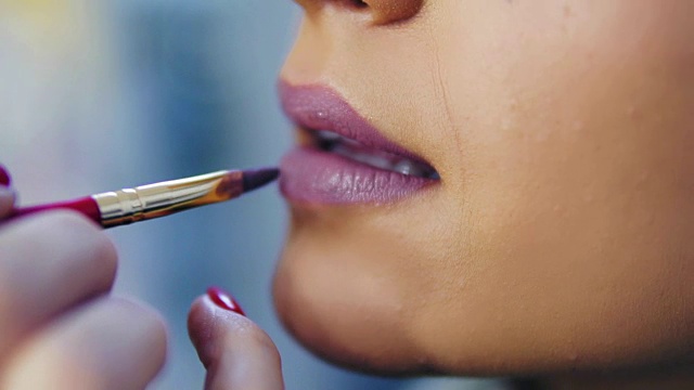 詳情圖-一個專業(yè)化妝師應用口紅的模特的嘴唇在美容時尚行業(yè)的特寫鏡頭。特寫的藝術家的手使用特殊的刷子。Slowmotion