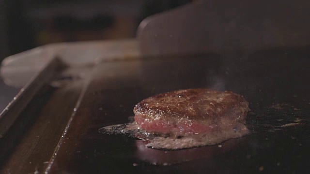 厨师用铲子烹饪和挤压肉质多汁的汉堡，街头小吃