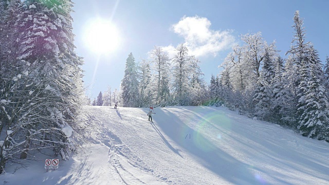 美丽的冬季景色，一些滑雪者滑下山坡