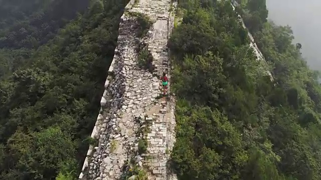 鸟瞰图的年轻的健身妇女越野跑跑在长城的顶端