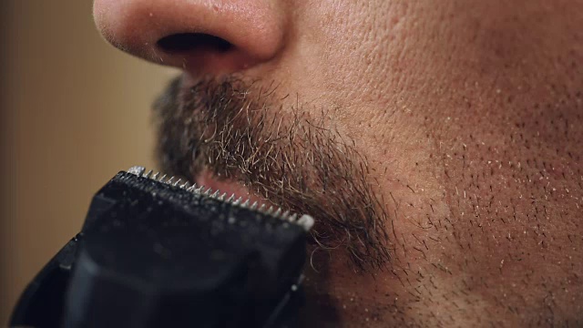 男性小心地梳理他的胡子与电动剃须刀，极端近距离