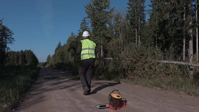 林业工人在森林道路上的电锯附近打电话