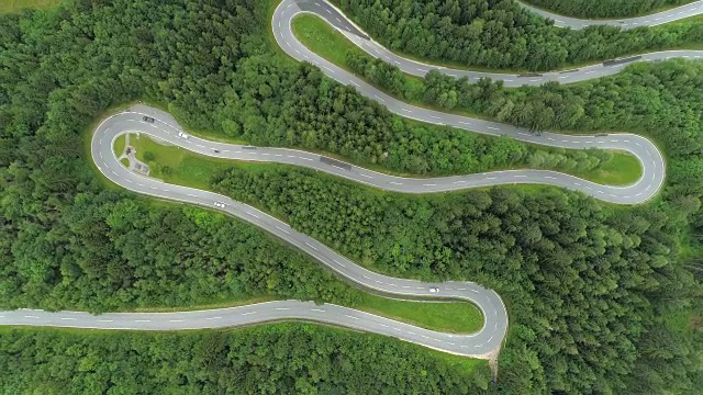 空中摄影:汽车在风景优美、弯弯曲曲、有急转弯的道路上行驶