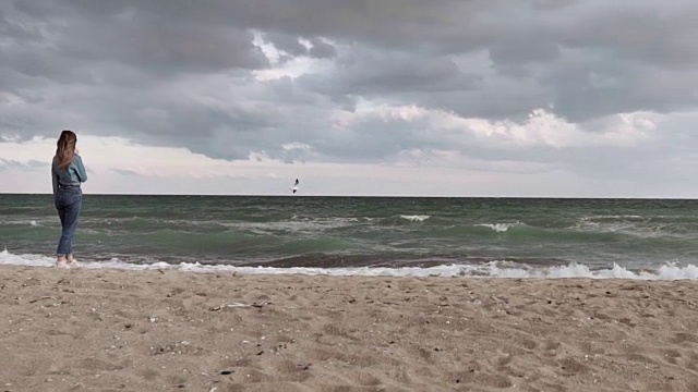 年轻美丽的女孩斯密斯在汹涌的大海岸边的一只飞翔的海鸥上