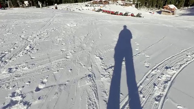 在雪地上行走的人的影子。带着头盔上的动作摄像头徒步登山，老兄
