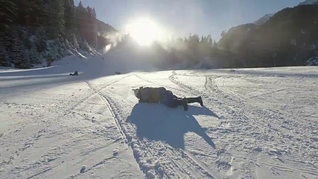 小女孩在雪地里打滚，滚下滑雪坡