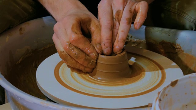 职业男性陶工在陶工轮上用粘土工作