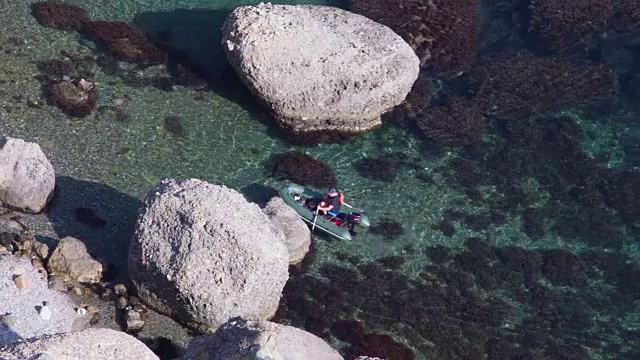 坐着一只充气船的人走近那块岩石